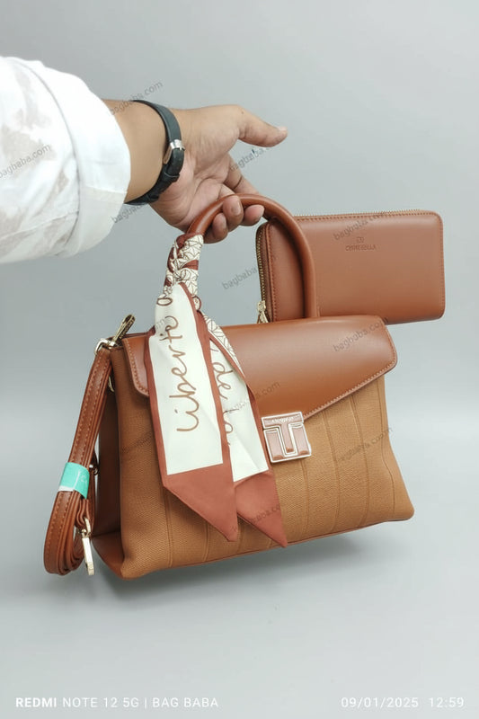 Brown handbag with a visible brand tag held by a person against a green grass background